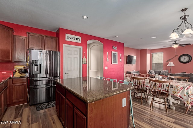 kitchen featuring ceiling fan, stainless steel fridge with ice dispenser, dark hardwood / wood-style flooring, pendant lighting, and a kitchen island