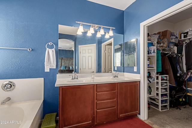 bathroom with a washtub, ceiling fan, and vanity