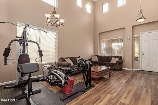 exercise area with hardwood / wood-style floors, a notable chandelier, and a high ceiling