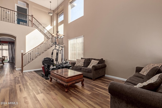 living room with a chandelier, wood-type flooring, and a high ceiling