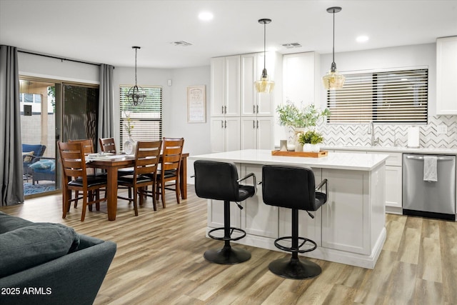 10617 W Daley Ln, Peoria, AZ 85383 - kitchen with stainless steel dishwasher, light countertops, white cabinetry, tasteful backsplash, and a center island