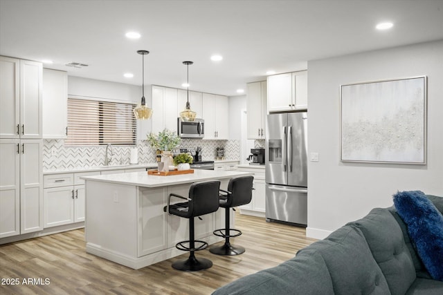 10617 W Daley Ln, Peoria, AZ 85383 - kitchen with appliances with stainless steel finishes, open floor plan, light countertops, white cabinetry, and a kitchen breakfast bar