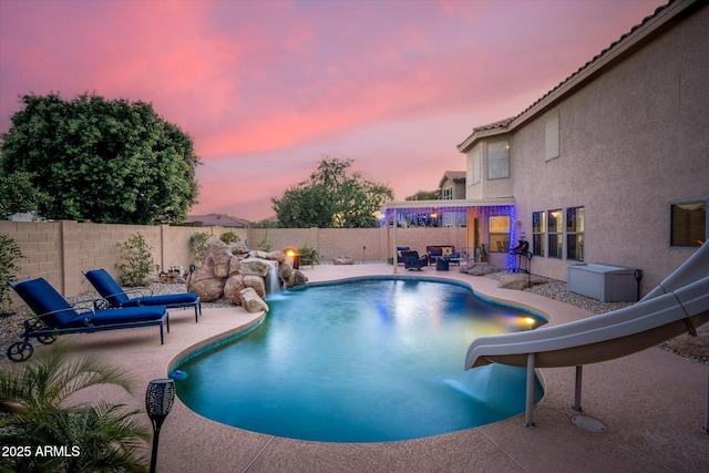 10617 W Daley Ln, Peoria, AZ 85383 - pool at dusk with a water slide, a patio area, and a fenced backyard