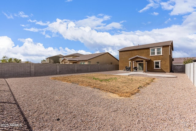 rear view of property featuring a fenced backyard, stucco siding, and a patio