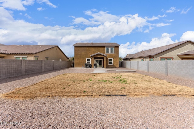 rear view of house with a fenced backyard, stucco siding, and a patio area