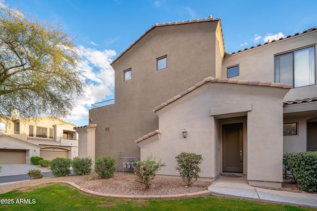 view of front of house featuring a tile roof, a balcony, and stucco siding