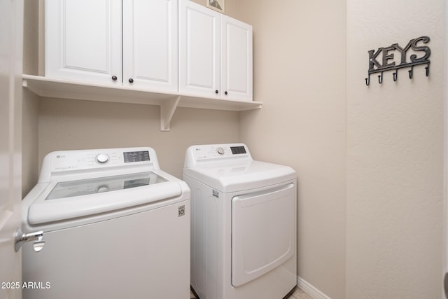 laundry room with washing machine and dryer, cabinet space, and baseboards