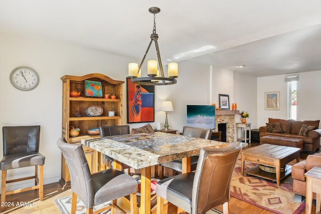 dining space with an inviting chandelier, a large fireplace, and light hardwood / wood-style floors