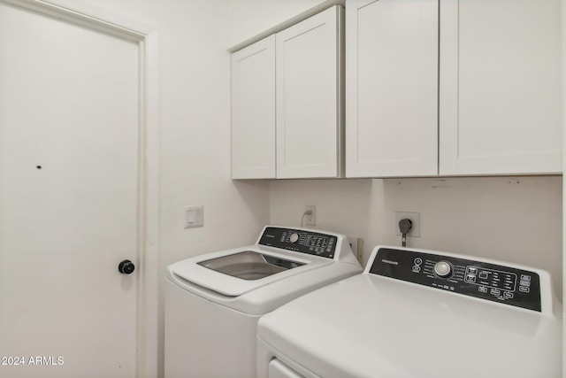 laundry room with separate washer and dryer and cabinets