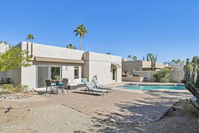 rear view of property featuring an outdoor living space, a fenced in pool, and a patio area