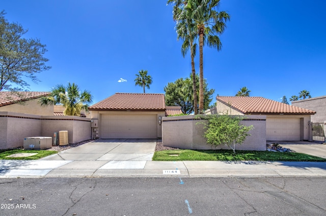 mediterranean / spanish-style home featuring fence, stucco siding, a tile roof, and a garage