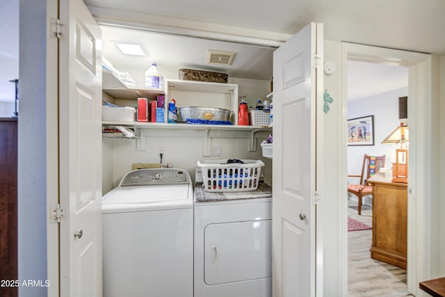 laundry room with laundry area, visible vents, washing machine and dryer, and light wood finished floors