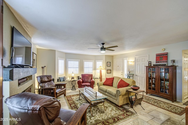 living area with ceiling fan and a fireplace