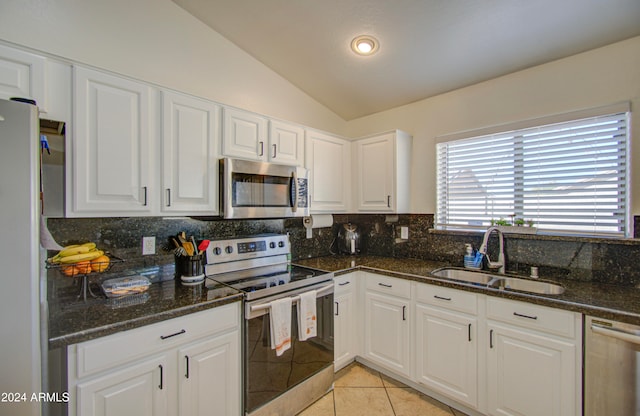 kitchen with lofted ceiling, sink, appliances with stainless steel finishes, and white cabinets