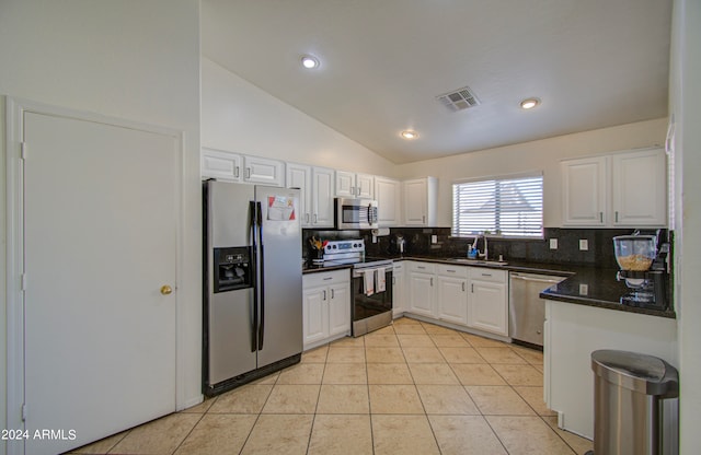 kitchen with appliances with stainless steel finishes, sink, vaulted ceiling, white cabinets, and light tile patterned floors