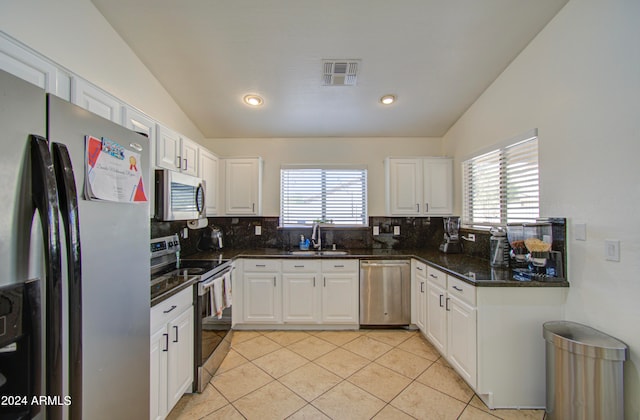 kitchen featuring vaulted ceiling, appliances with stainless steel finishes, and white cabinetry