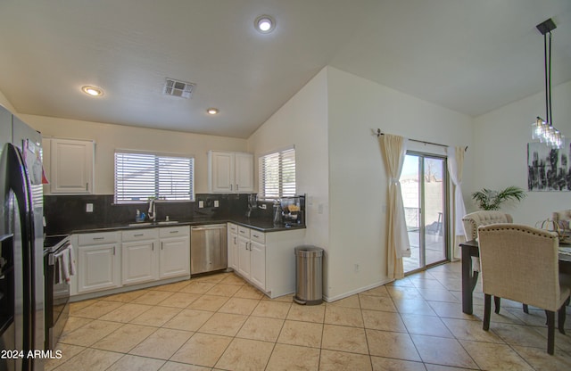 kitchen featuring lofted ceiling, stainless steel appliances, sink, pendant lighting, and white cabinetry