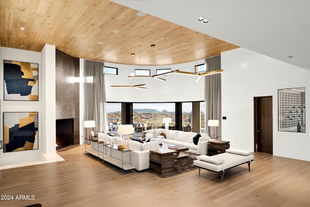 living room featuring a towering ceiling, light wood-type flooring, and wooden ceiling