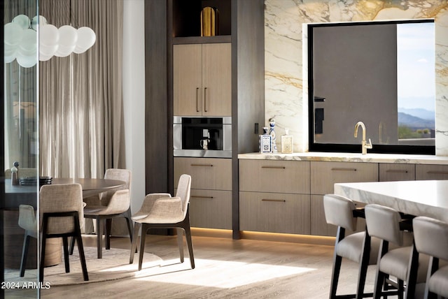 bar with a mountain view, stainless steel oven, light hardwood / wood-style floors, and light brown cabinetry