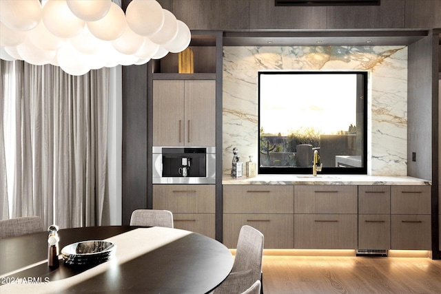 kitchen featuring stainless steel oven, light wood-type flooring, and sink