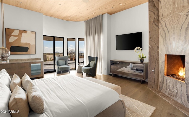 bedroom with wood ceiling, light wood-type flooring, and a high ceiling