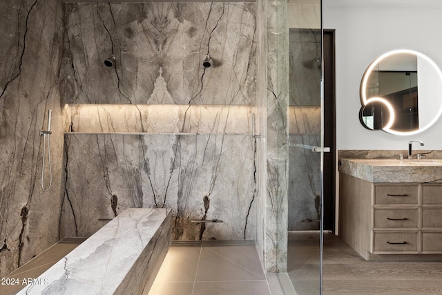 bathroom featuring tile walls, vanity, tiled shower, and tile flooring