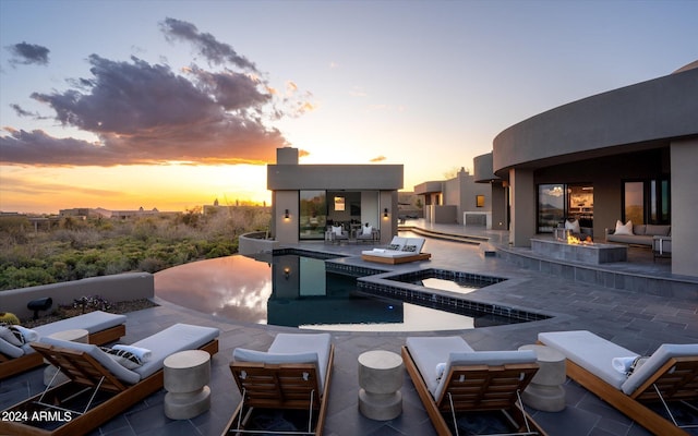 patio terrace at dusk with a pool with hot tub