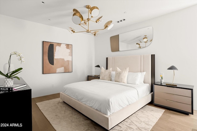 bedroom with a notable chandelier and light wood-type flooring