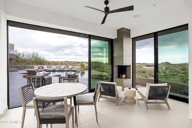 interior space with ceiling fan, a water view, light tile floors, and plenty of natural light