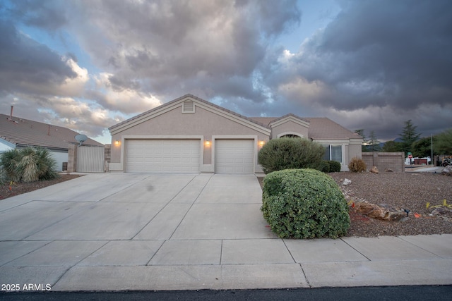 ranch-style house featuring stucco siding, a gate, fence, concrete driveway, and an attached garage