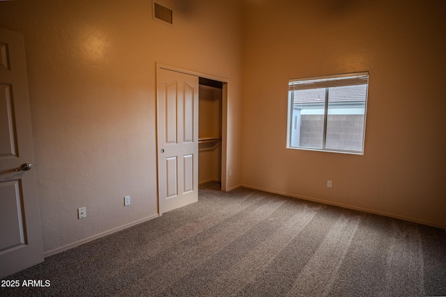 unfurnished bedroom with visible vents, baseboards, a closet, carpet flooring, and a textured wall