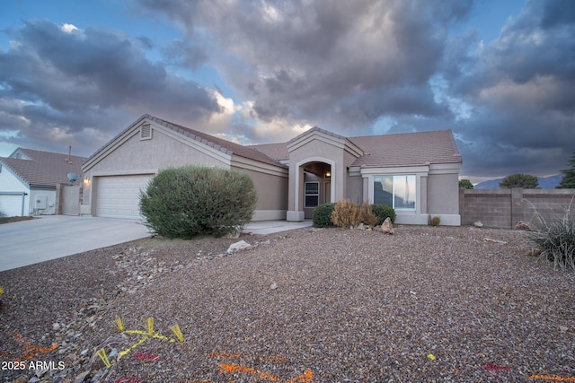 view of front of property with stucco siding, driveway, fence, a garage, and a tiled roof