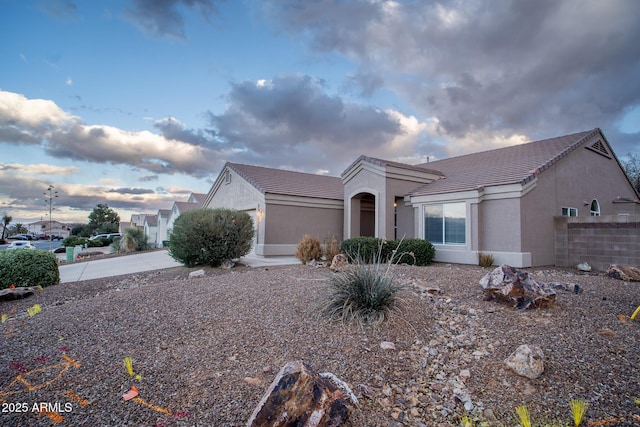 view of property exterior with a tile roof, stucco siding, an attached garage, and concrete driveway