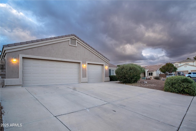 view of side of home featuring stucco siding, a garage, and driveway