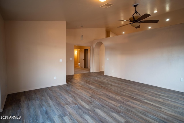 empty room featuring visible vents, wood finished floors, arched walkways, and ceiling fan