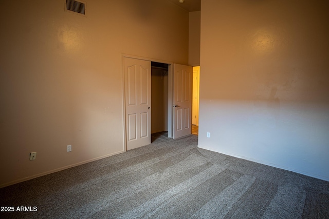 unfurnished room featuring a high ceiling, visible vents, and carpet floors