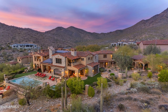 10935 E Grandview Way, Scottsdale, AZ 85255 - back of house at dusk featuring solar panels, a patio, a chimney, a tiled roof, and a mountain view