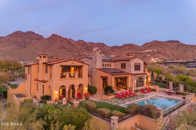 rear view of house with a fenced backyard, a mountain view, a balcony, an outdoor pool, and a patio area