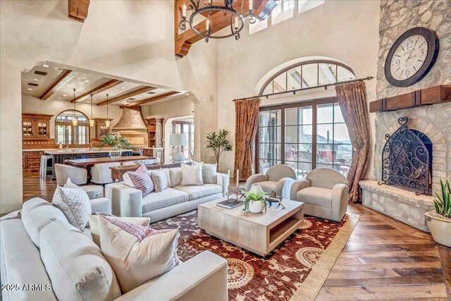 10935 E Grandview Way, Scottsdale, AZ 85255 - living area featuring a chandelier, a large fireplace, a towering ceiling, beam ceiling, and hardwood / wood-style floors