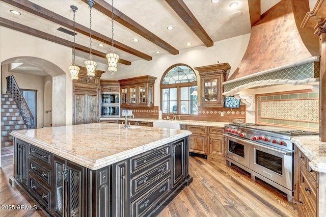 10935 E Grandview Way, Scottsdale, AZ 85255 - kitchen featuring arched walkways, range with two ovens, visible vents, and tasteful backsplash