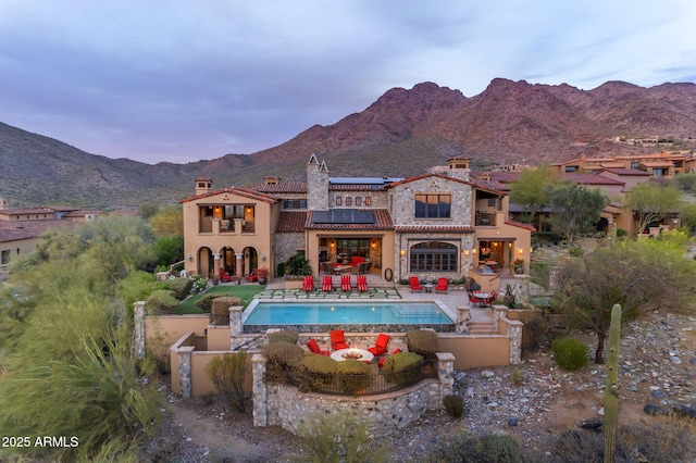 10935 E Grandview Way, Scottsdale, AZ 85255 - back of property with a mountain view, roof mounted solar panels, an outdoor pool, a chimney, and a patio area