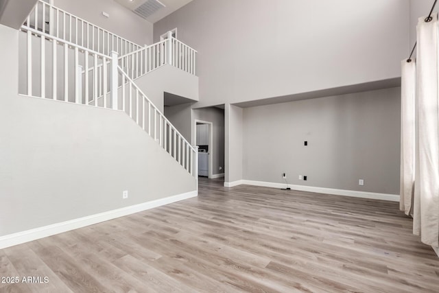 unfurnished living room featuring light hardwood / wood-style floors and a high ceiling