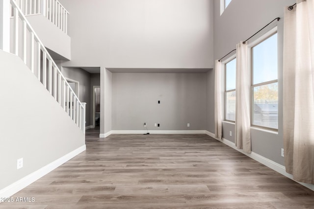 unfurnished living room with light hardwood / wood-style flooring and a high ceiling