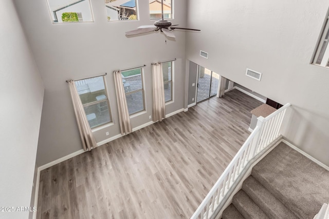 staircase with hardwood / wood-style flooring, ceiling fan, and a high ceiling