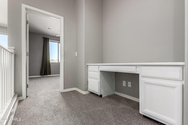 unfurnished office featuring carpet floors and built in desk