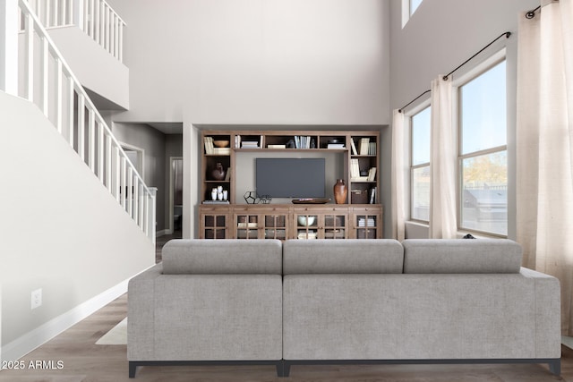 living room featuring a towering ceiling and hardwood / wood-style floors