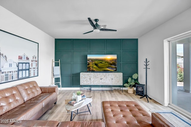 19736 W Turney Ave, Litchfield Park, AZ 85340 - living area featuring light wood-type flooring, a wood stove, a ceiling fan, and baseboards