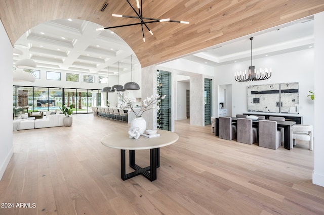 living room with a chandelier, beam ceiling, coffered ceiling, light hardwood / wood-style flooring, and a high ceiling