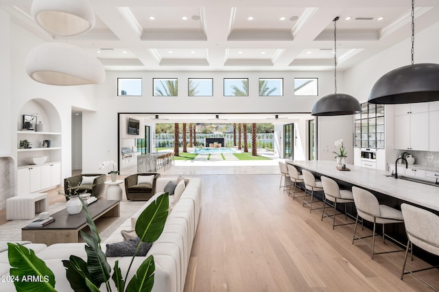 living room with beamed ceiling, light wood-type flooring, and a wealth of natural light