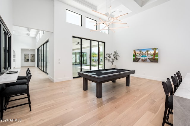 recreation room with pool table, light hardwood / wood-style floors, beam ceiling, coffered ceiling, and a towering ceiling